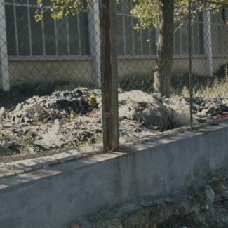 Krpe trikotaže pored zida unutar tvorničkog kruga na hrpama pored puta - prilaz rijeci